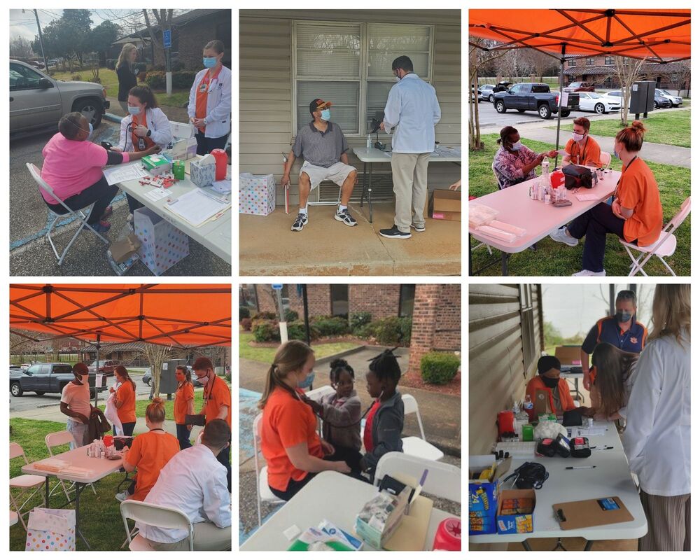 Residents receiving health screenings under orange tent surrounded by students from Auburn University