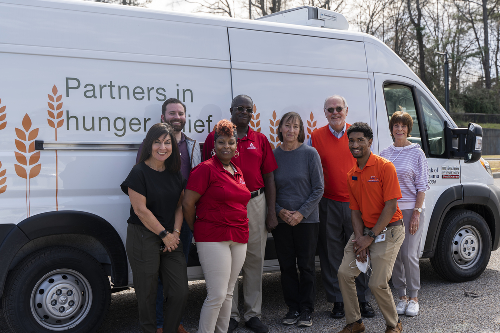 Staff members and volunteers standing in front of Food Bank of East Alabama van