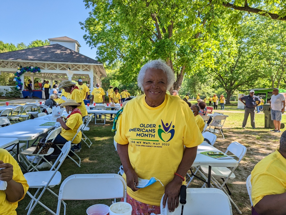 Older Lady smiling with her hand on folding chairs