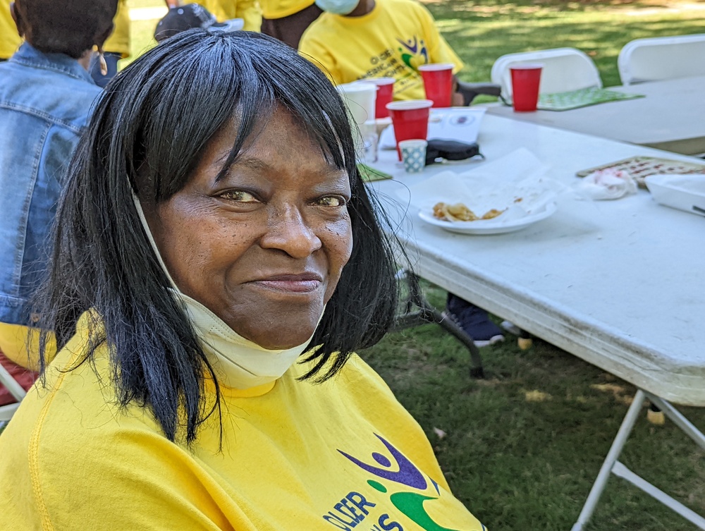 Older Female with mask below her chin smiling 