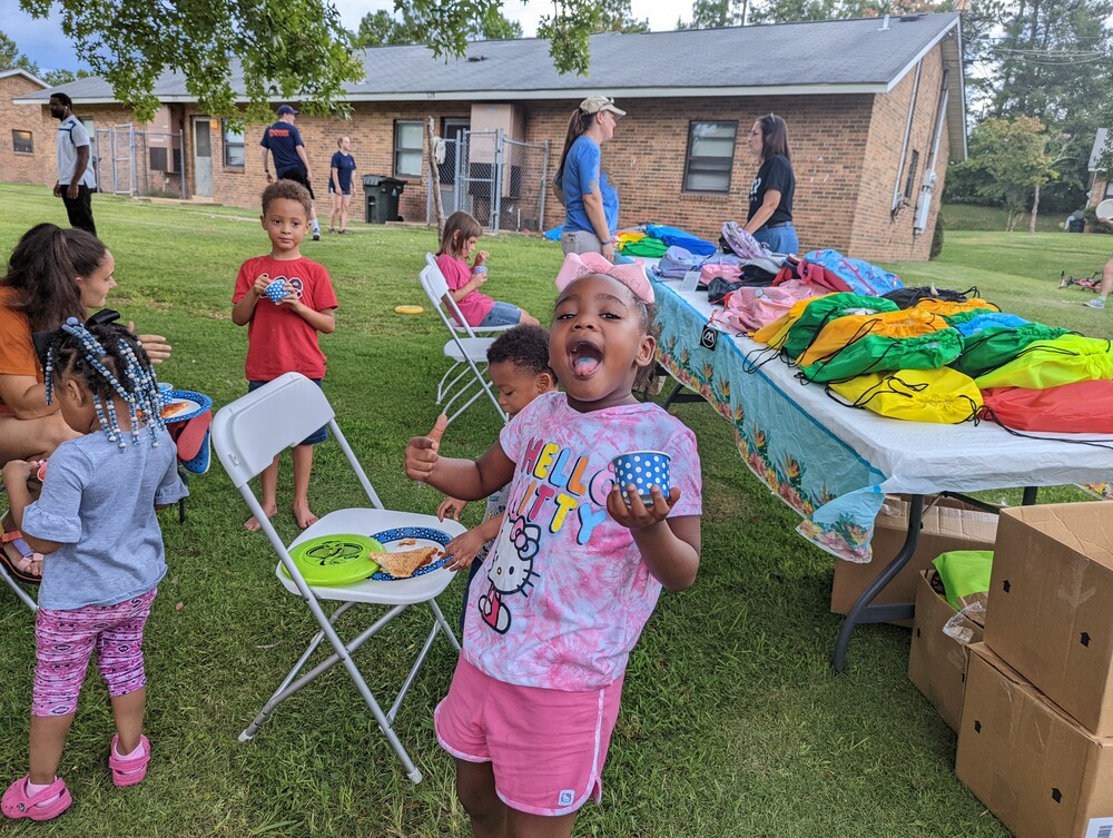 AHA Back to school young girl in pink smiling showing off the food in her mouth