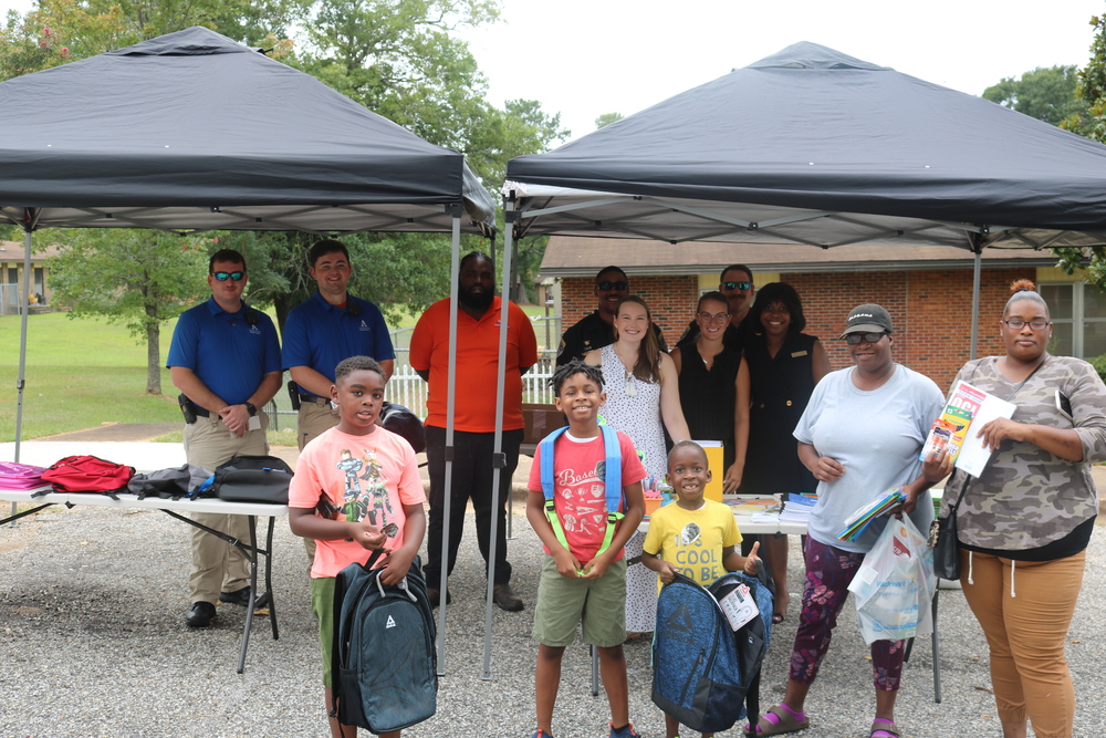 youth receiving backpacks are smiling in front of vendor table