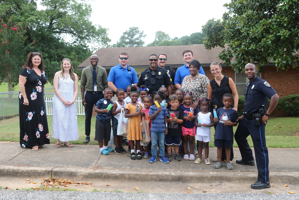 Auburn police department officers standing with youth having received supplies and auburn housing staff