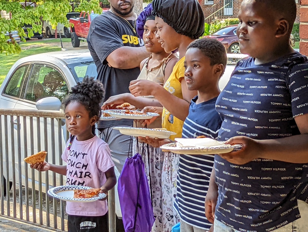 RHA Back To School youth looking on while holding pizza in paper plates