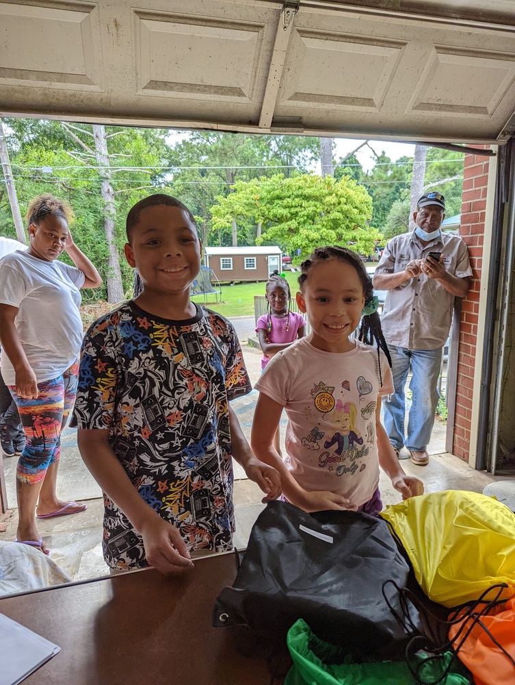 RHA Back to School two kids smiling under tent in front of new back pack display