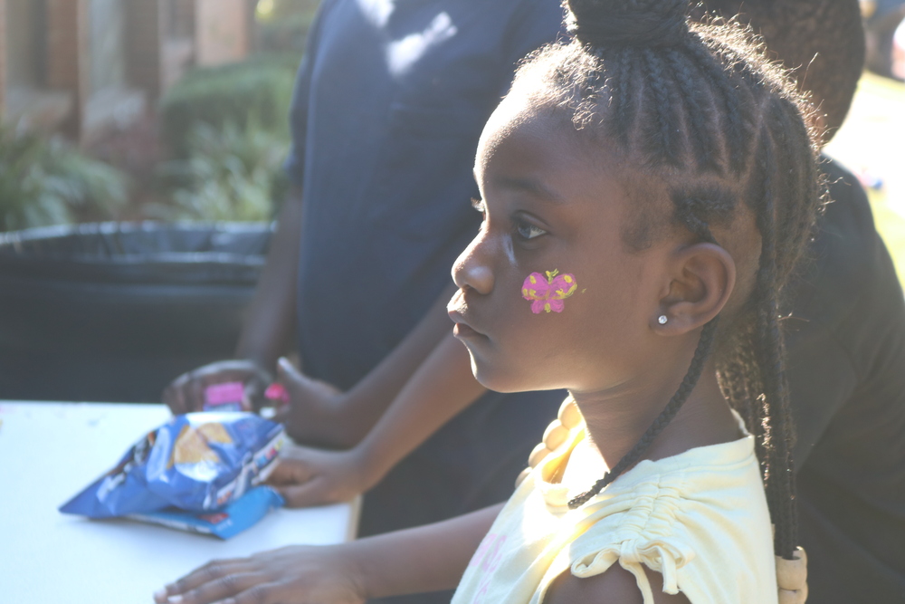 LaFayette Tailgate party young girl looking on with her face painted and braids