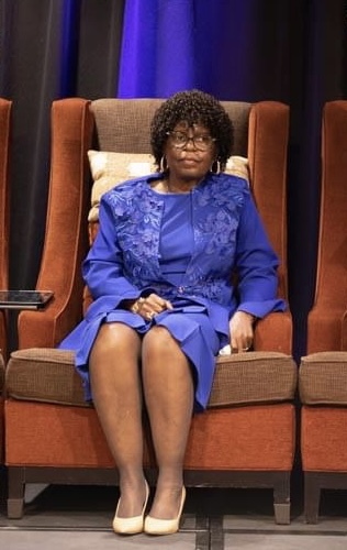 Lady in blue dress sitting on panel at scholarship breakfast