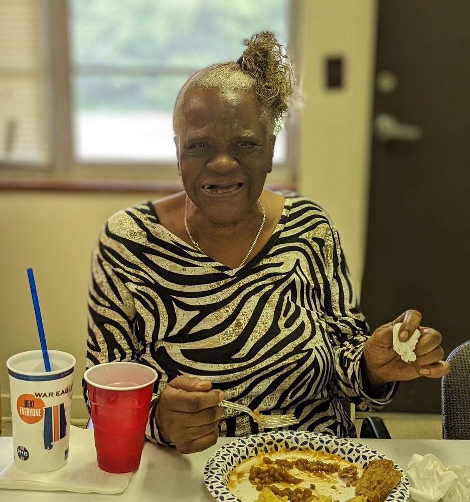 Older wonderful wednesday female attendee smiling with her hair in ponytail at table