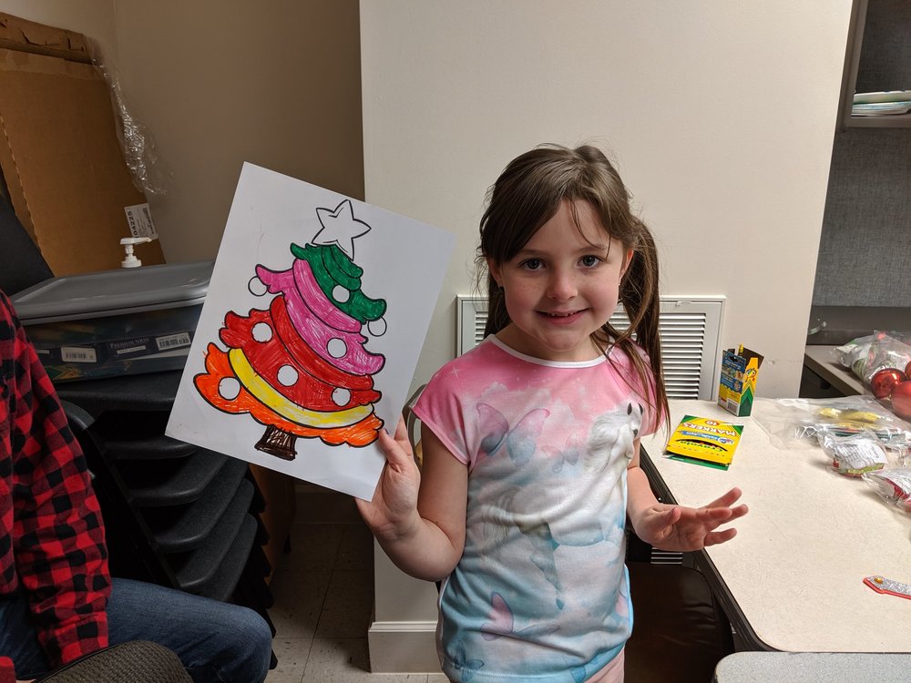 little girl showing off her christmas tree coloring sheet