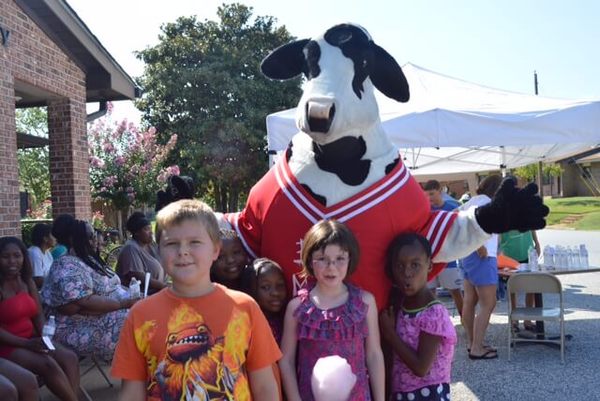 Youth National Night Out attendees posing with the Chick-fil-a cow mascot. 