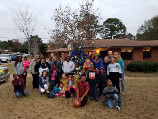 Youth posing for picture outside under a decorated tree.