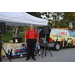 Praise 88.7 host posing for picture in front of vendor table and the 88.7 van.