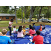 Youth on a large blue mat watching a Church of the Highlands staff member carving a pumpkin.