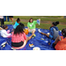 Youth on a large blue mat listening to Church of the Highlands staff member reading a book.