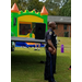 Police Officer watching block party festivities near a castle jump house. 