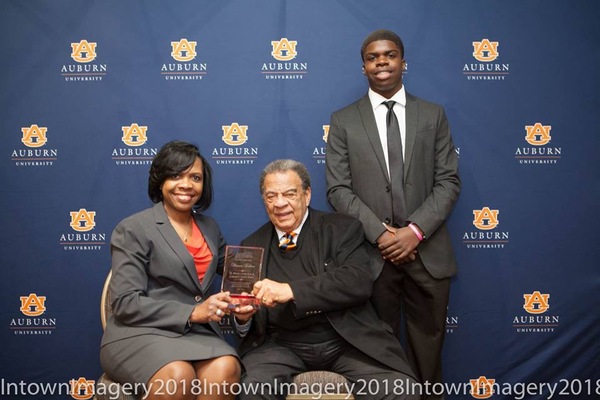 CEO Sharon Tolbert holding plaque with guest and son at 2018 MLK Scholarship Breakfast