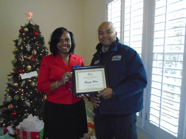 CEO Sharon Tolbert presenting employee Gregory Moore a 5 year anniversary plaque.