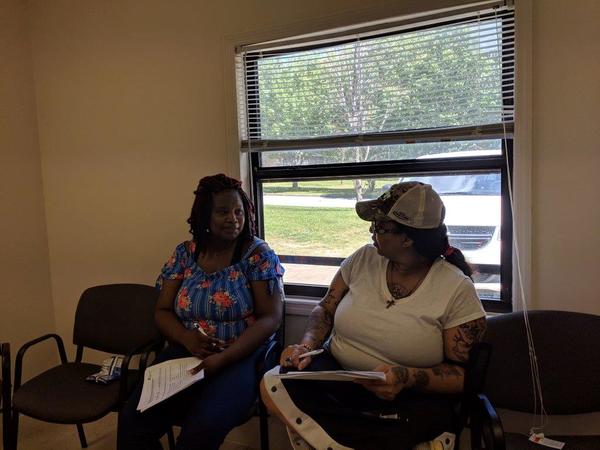 Two females holding paperwork and discussing homeownership