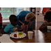 Our House Auburn volunteer speaking with a young boy during breakfast