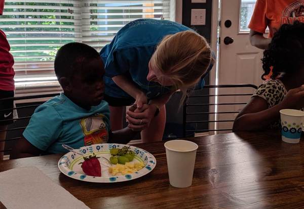 Our House Auburn volunteer speaking with a young boy during breakfast