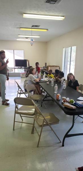 Vacation Bible School youth attendees eating snacks at folding tables 