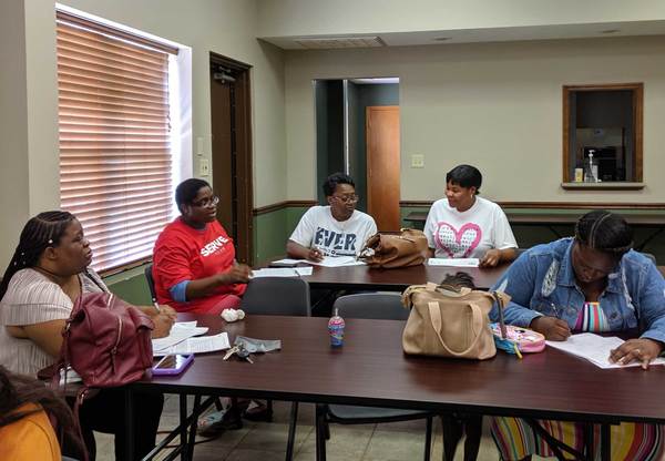 Family Self-Sufficiency program attendees talking and completing paperwork at table