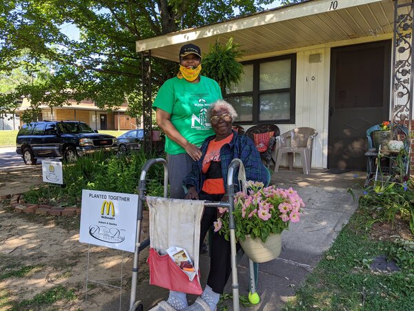 Senior resident in walkway with potted plants smiling