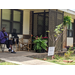 Senior resident sitting in chair on front porch with potted plants 