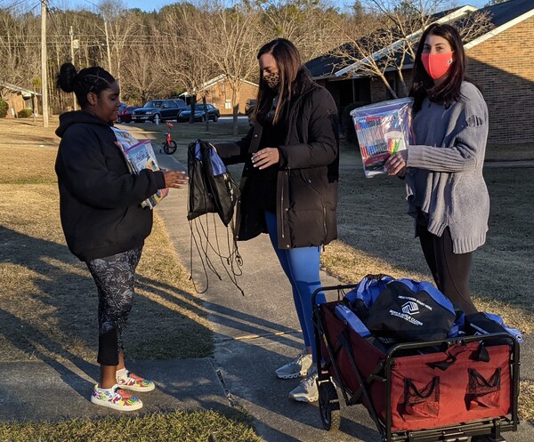 Female Student receiving school supplies from AHA Staff