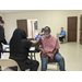 Female administering Pfizer vaccine to male participant with red shirt 