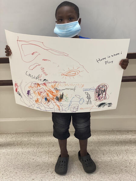 Youth resident holding up his \'What Home Means to Me\' poster drawing