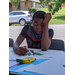 Youth resident with hand on head using marker to draw on poster 