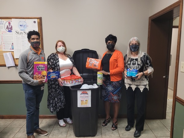 AHA Staff holding non perishable food donations to support food drive.