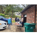 Community members outside talking between car and brick building