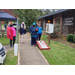 Community members talking near little library and corn hole setup