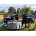 Auburn Police Officers standing behind their vendor table and in front of police vehicles
