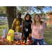 Three female standing behind a pumpkin themed vendor table smiling