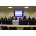 Members of the Auburn Housing Authority Staff are seated behind a long rectangular table posing for a group picture.  While the tv projector is in the background behind them.
