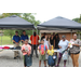 Auburn Housing Authority staff are under tents as youth and families receiving school supplies are standing in front of tents posing for camera