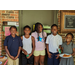 A group of 5 elementary aged youth are standing out in front of the LaFayette offices smiling and one has a paper plate with slice of pizza on it.