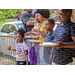 Youth with their backs up against a fence are holding paper plates with pizza and snacks.