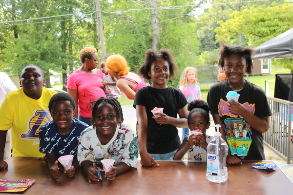 Youth smiling and eating snow cones at the tailgate event