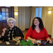 Two female employees in mid conversation at Christmas luncheon