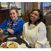 Two female employees posing together while sitting behind table at Christmas Luncheon