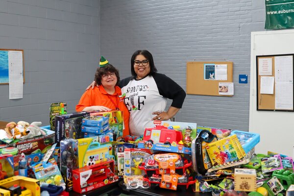 Charlotte Mattox and Tabitha Griffin standing behind a table of toys at the Auburn Public Safety Toy Drive