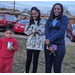 Family ourside in front of cars with snacks at Christmas event