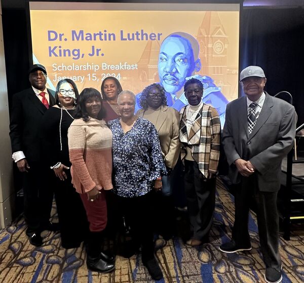 Scholarship Breakfast attendees standing in front of MLK background