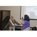 Female is taking a picture using her camera phone of Sandra Sanders in a retirement celebration sash