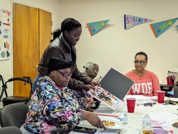 Senior citizens participating in BraveHearts luncheon activities with volunteer 