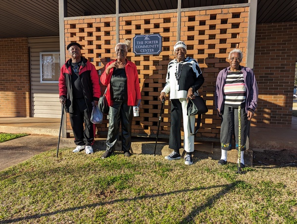 Group of senior citizens standing outside Porter Community Building brick wall in winter attire 